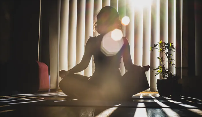 Lady meditating on the floor with legs crossed